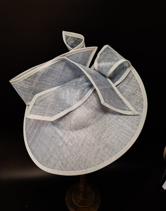 baby blue sculptured sinamay fascinator on a mannequin head in a dark background